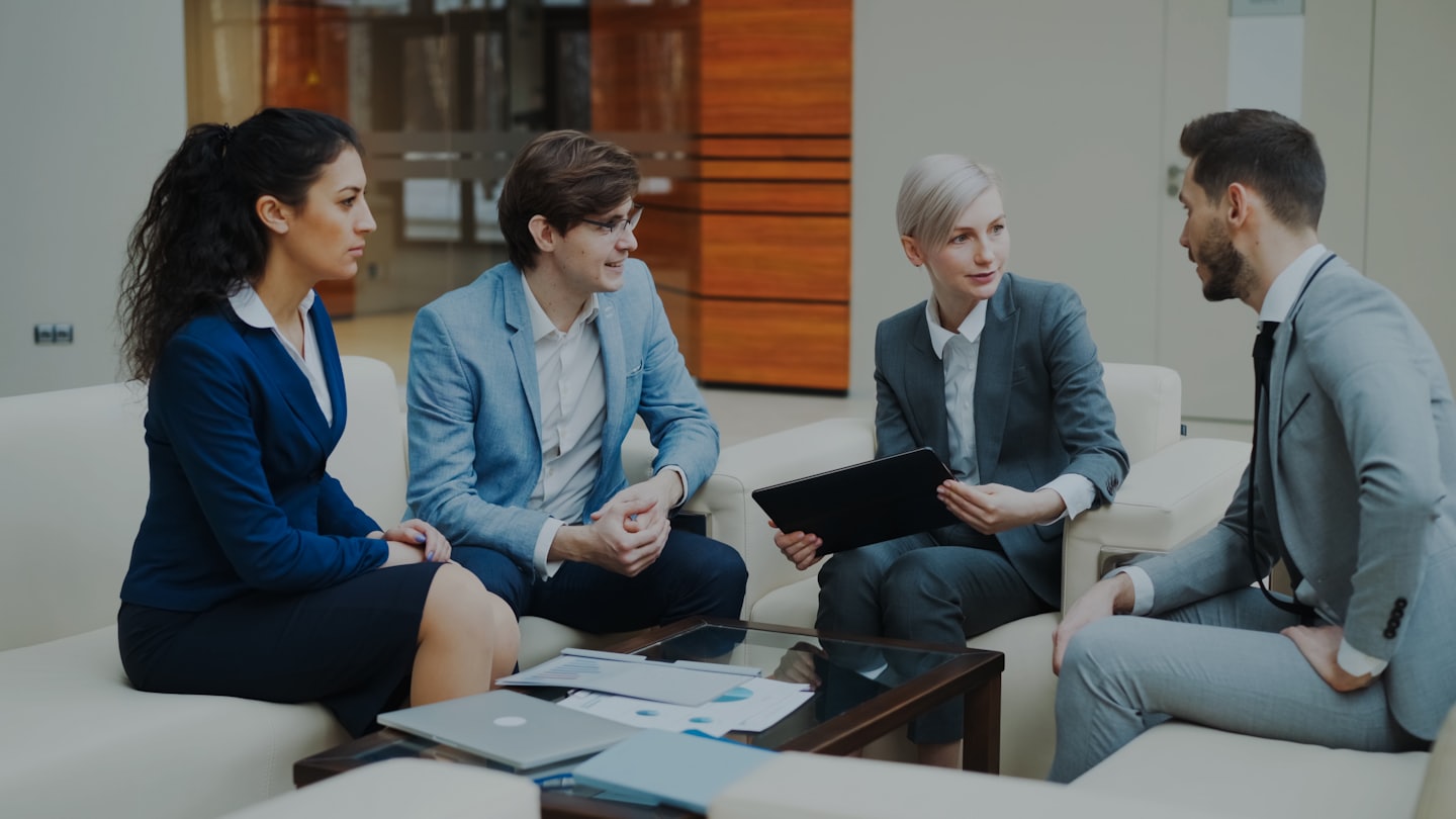 Business professionals collaborating around a coffee table in an office.